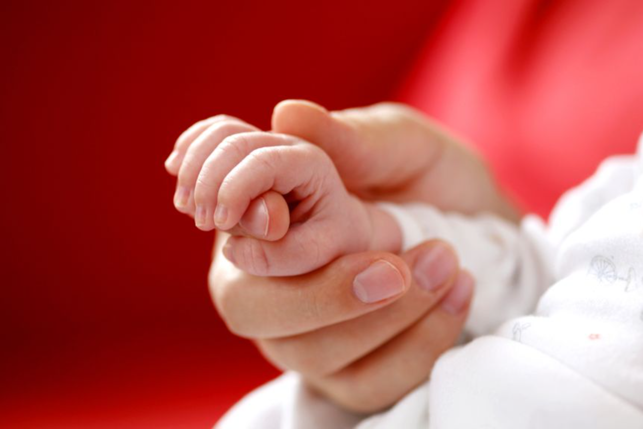 Lächelndes Baby in den Armen einer Ärztin im weißen Kittel